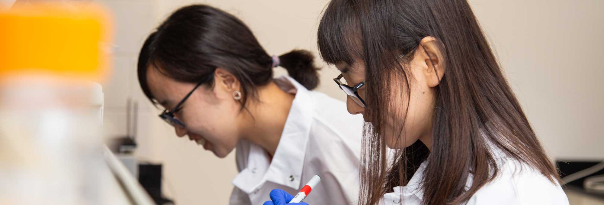 two lab workers laugh and smile while working