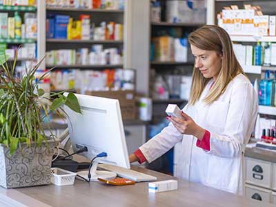 a pharmacist checks the price of a medication in a computer