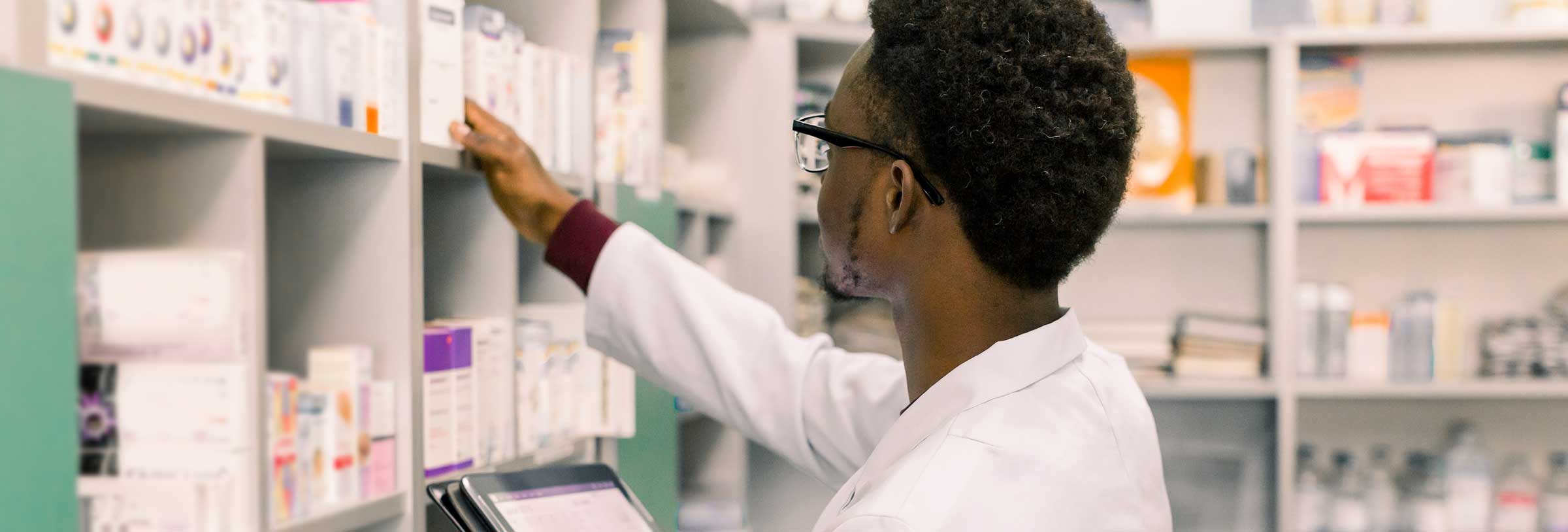 a pharmacy technician uses a digital tablet to inventory the shelves in a retail pharmacy